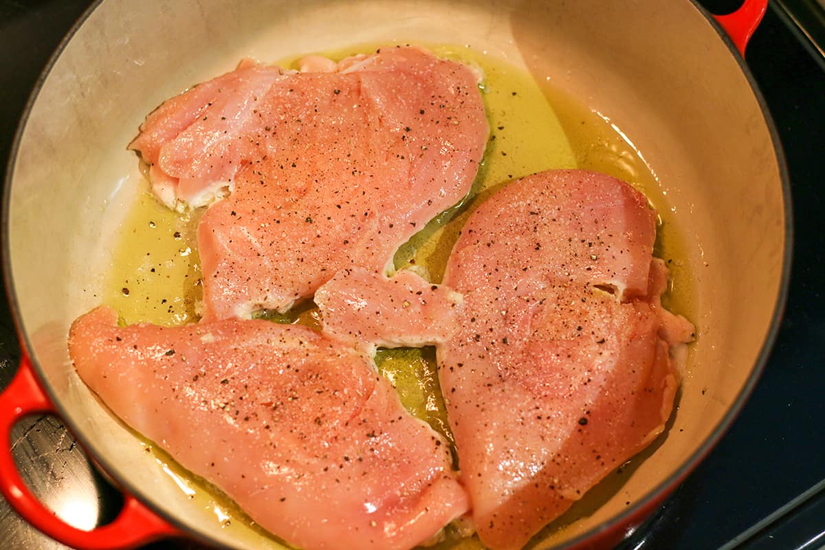 A large dutch oven white chicken breasts being cooked.