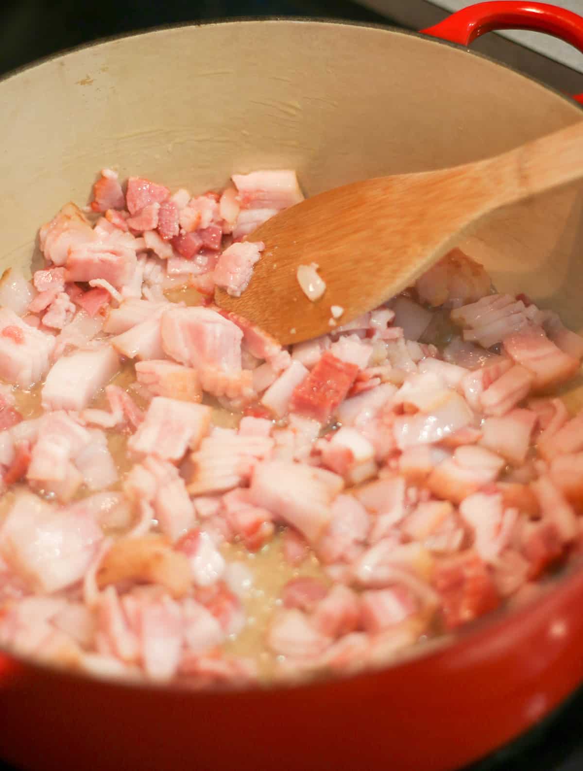 Diced bacon cooking in a large Dutch Oven.