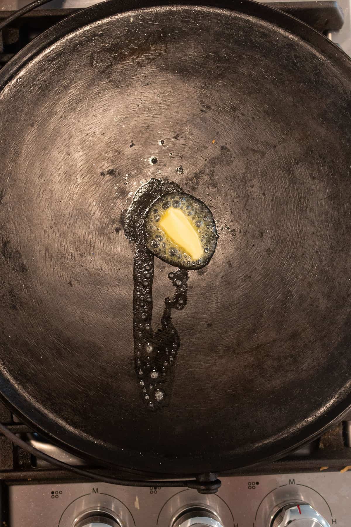 Butter being melted on a cast iron griddle.