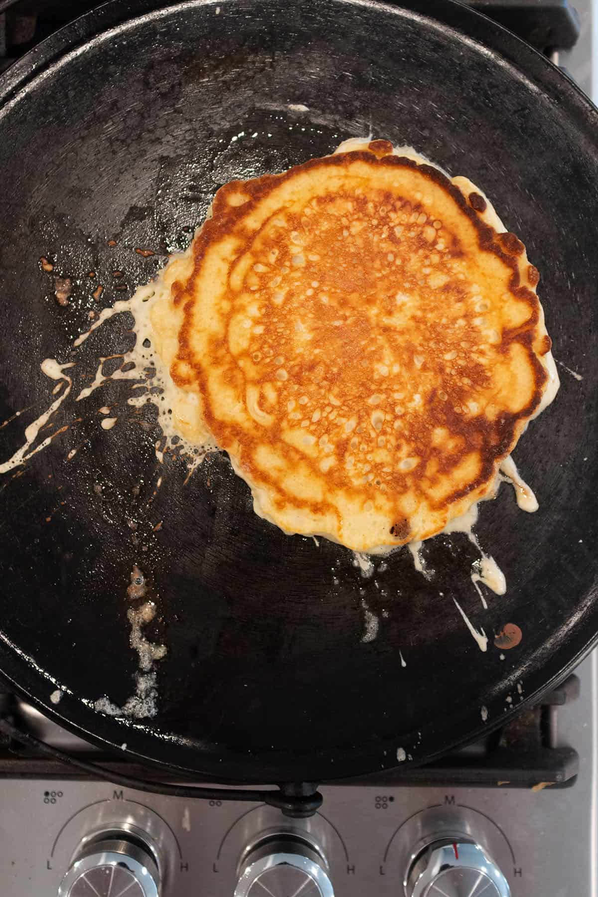 Sourdough pancake being cooked on a cast iron griddle.