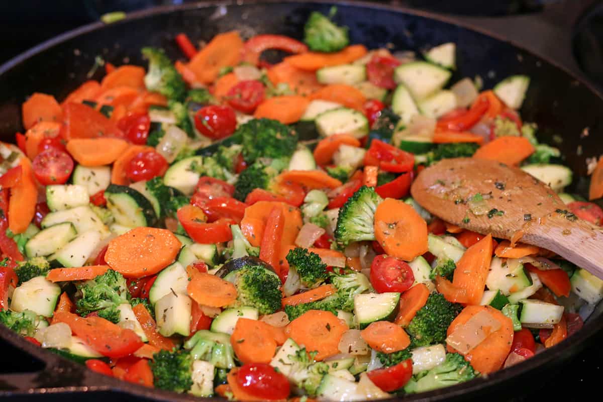 Cast iron pan with sauted veggies. Carrots, broccoli, carrots, onions and zucchini.