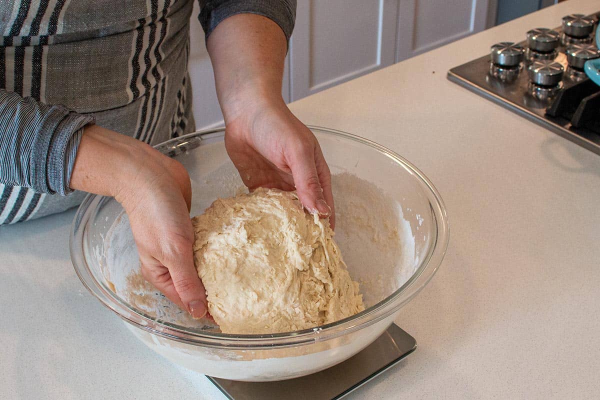 Hands working the dough into a rough ball.