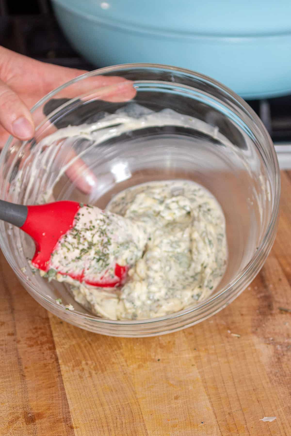 Mixing bowl with a spatula creaming together butter and herb mix.