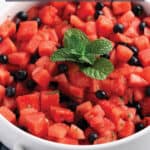 White serving tray with diced up watermelon, blueberries and fresh mint.