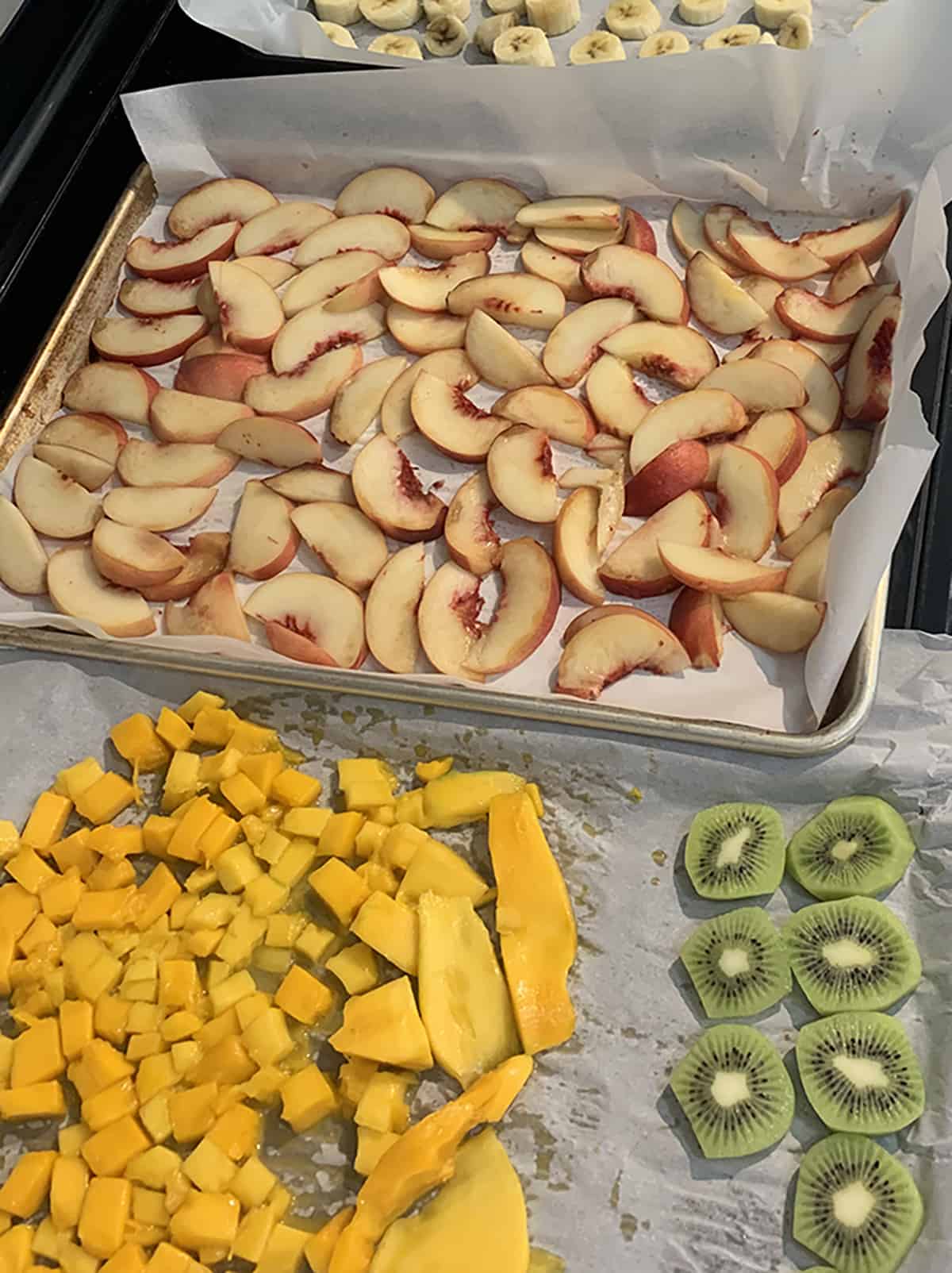 Fresh slices of peaches, banana and kiwi on parchment paper. 