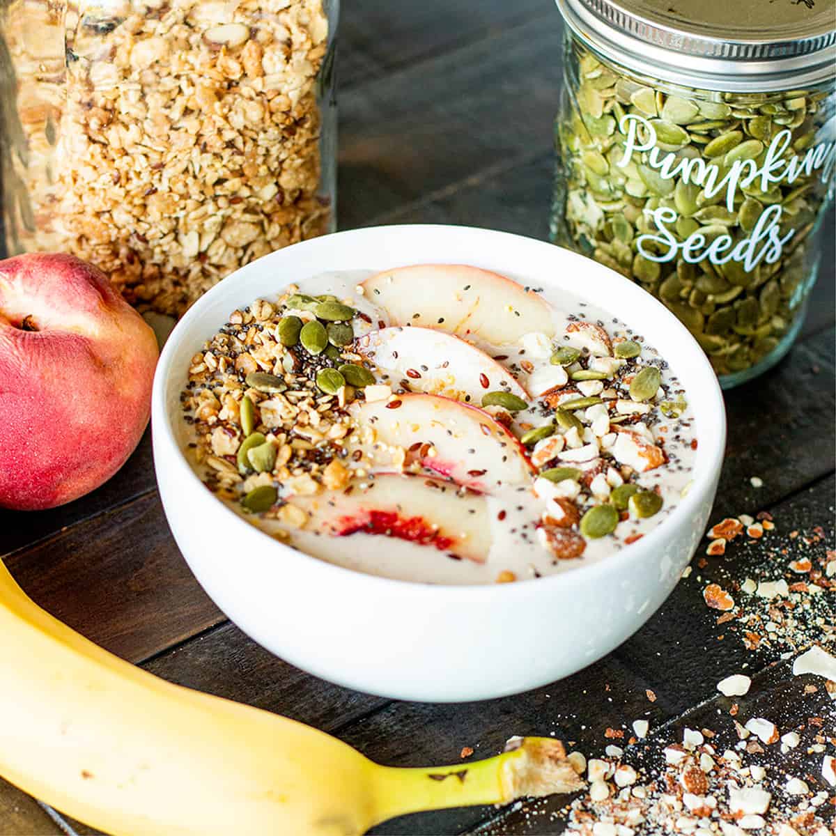 Bowl with a peach banana smoothie with nuts, granola and fresh peaches. 