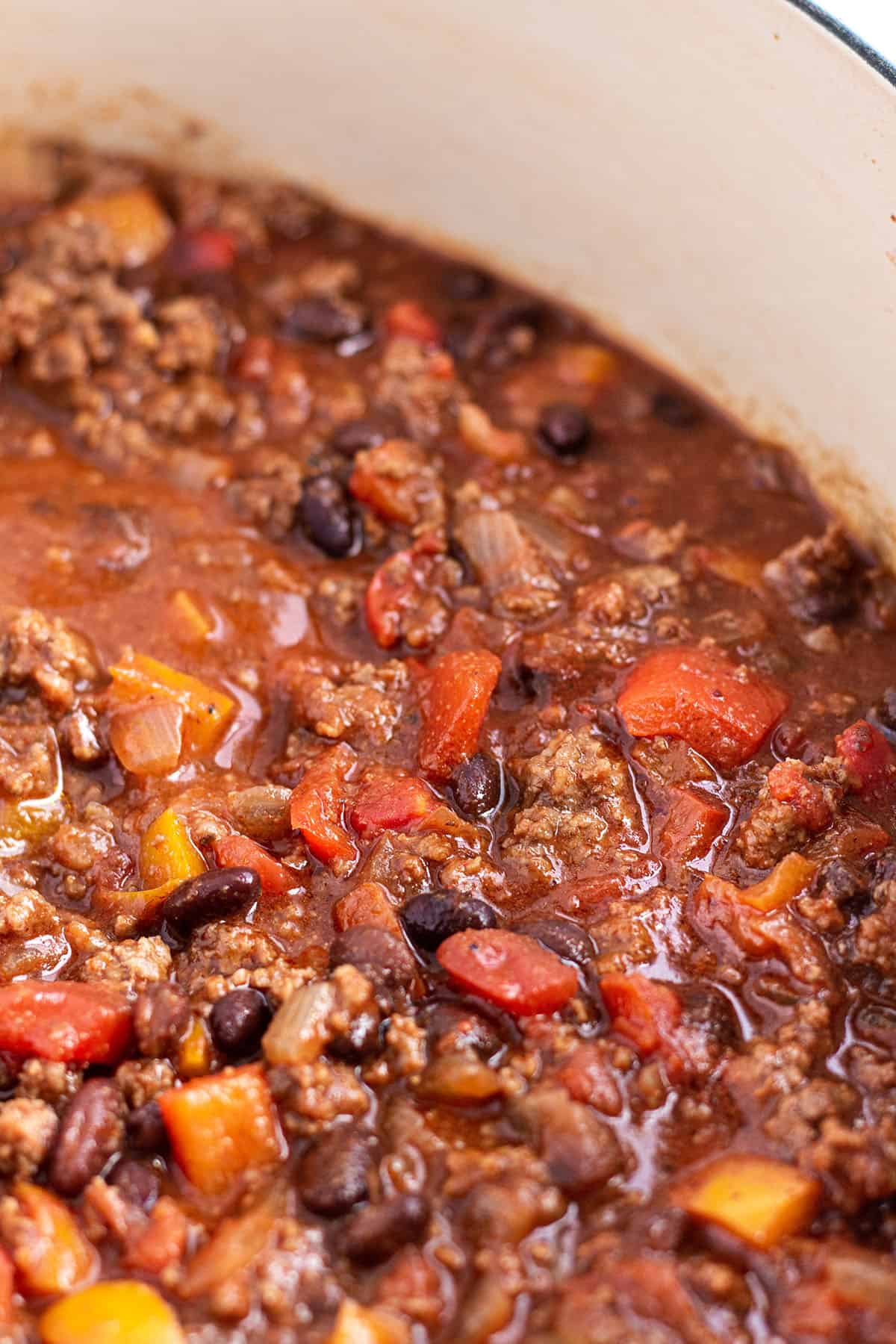 A large Dutch Oven with a homemade chili full of ground beef, black beans and peppers. 