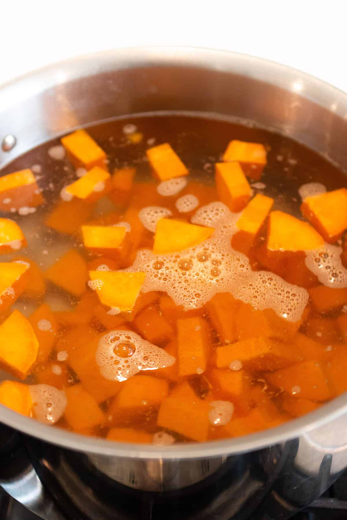 A large pot with boiling water and diced sweet potatoes.