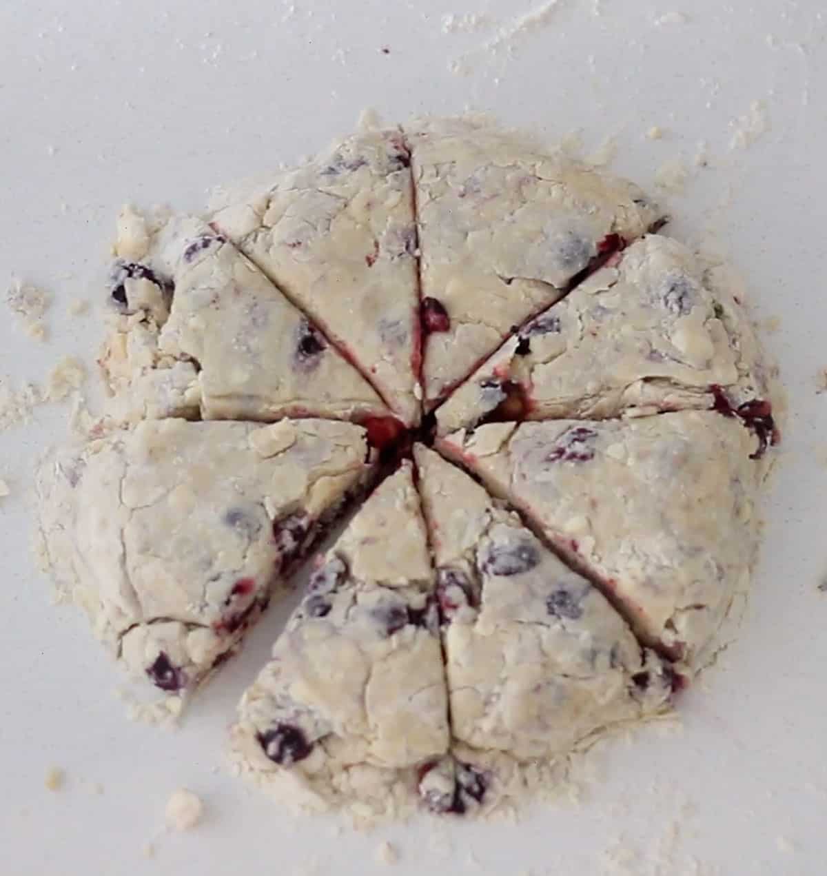 Dough shaped into a circle with 8 triangles cut into it. 