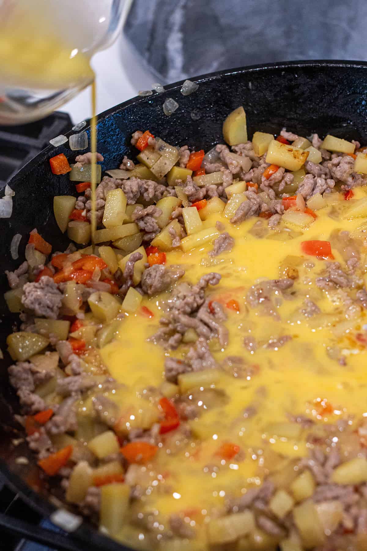 Breakfast enchilada filling being cooked in a cast iron pan. 