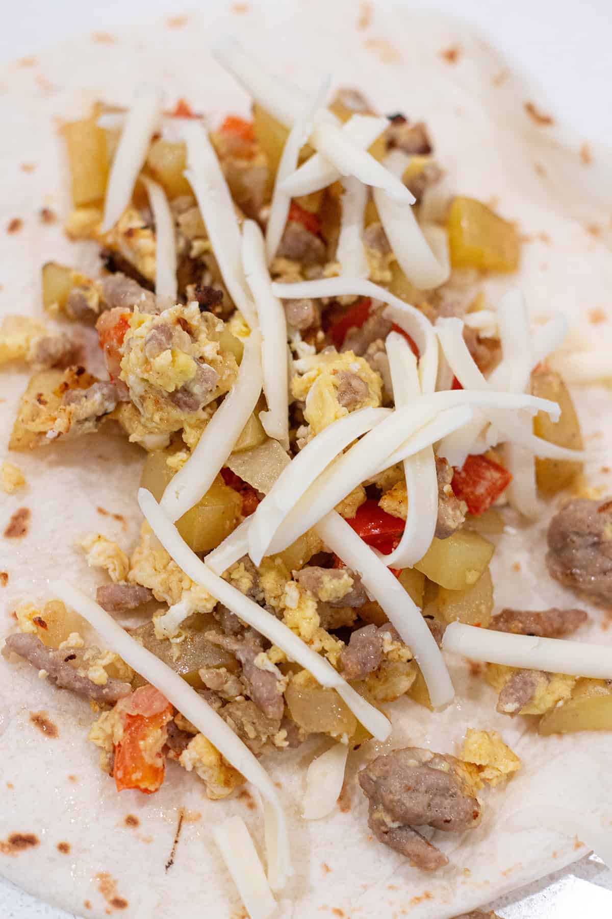 Tortilla shell with breakfast sausage, potatoes, peppers, eggs and cheese.