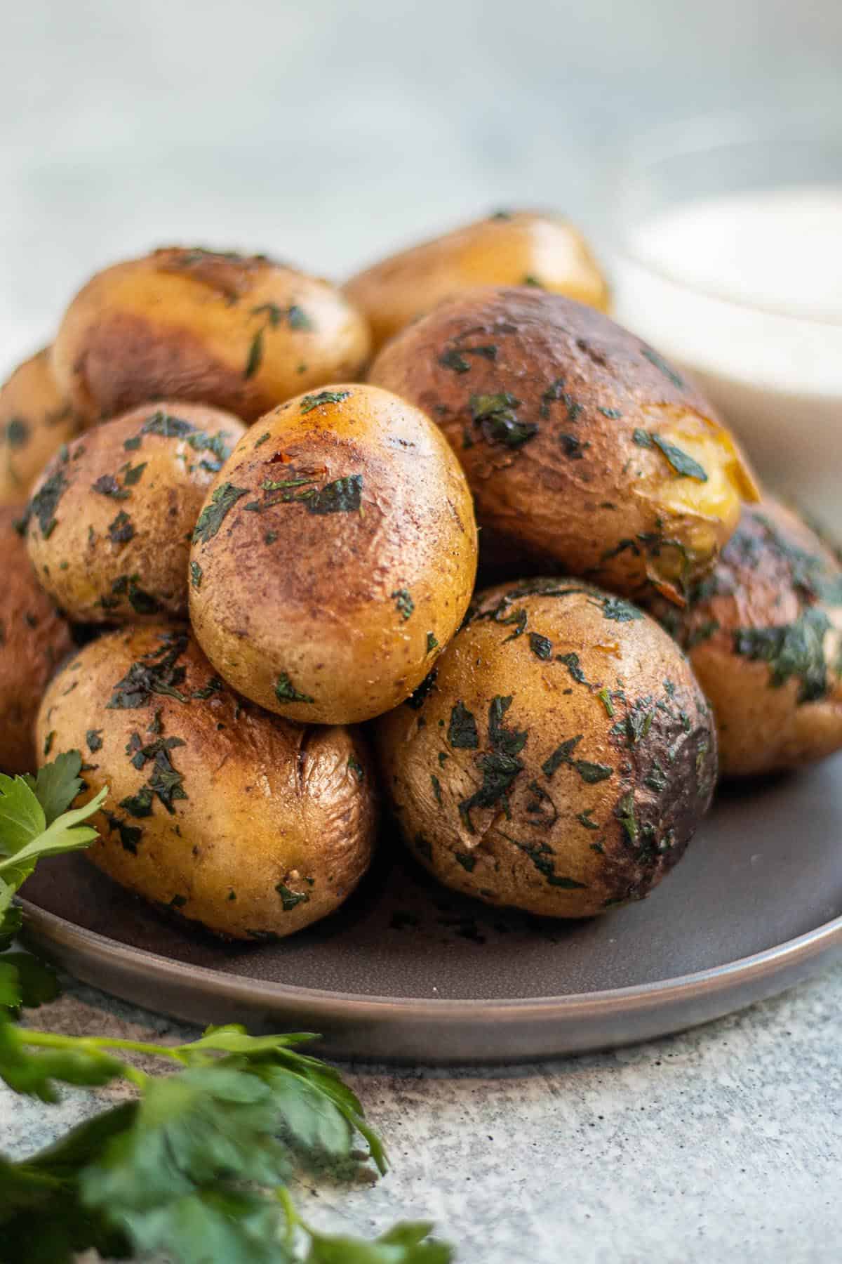 A pile of yukon gold potatoes with fresh herbs and butter. 