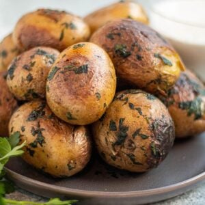 A plate with a stack of Yukon gold potatoes covered in herbs.