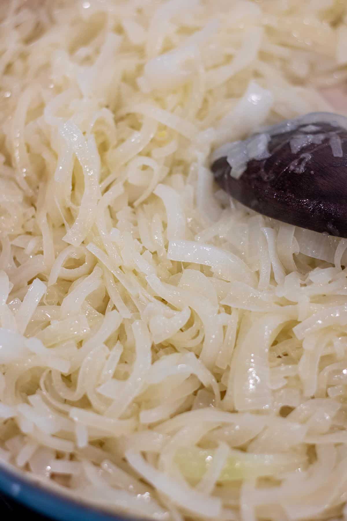 Sautéed onions that are silky looking with a wooden spoon.