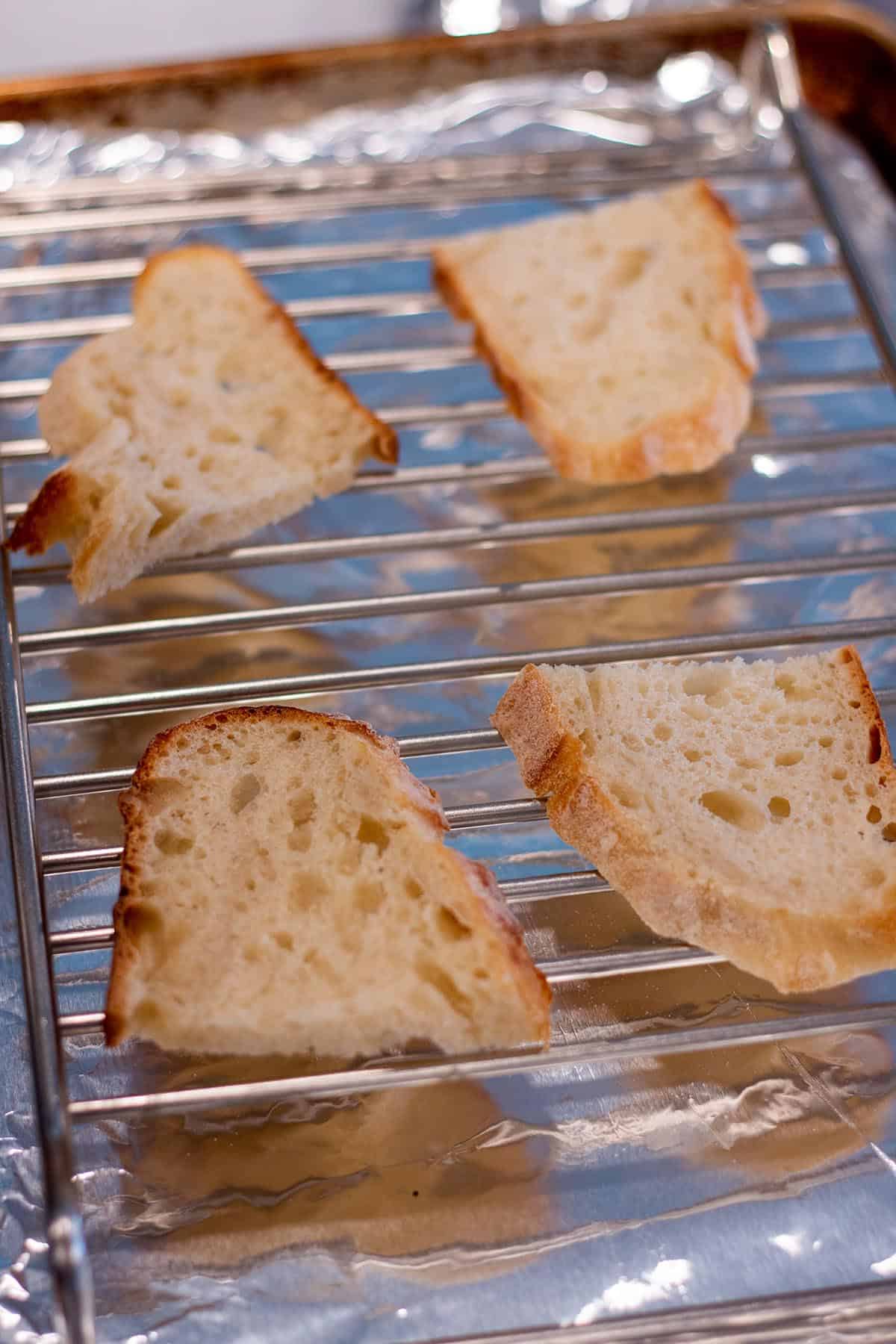 A baking sheet with wire rack and four slices of bread.