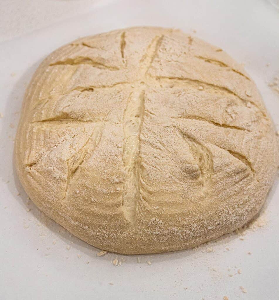 a freshly scored loaf of sourdough bread about to go in the oven.
