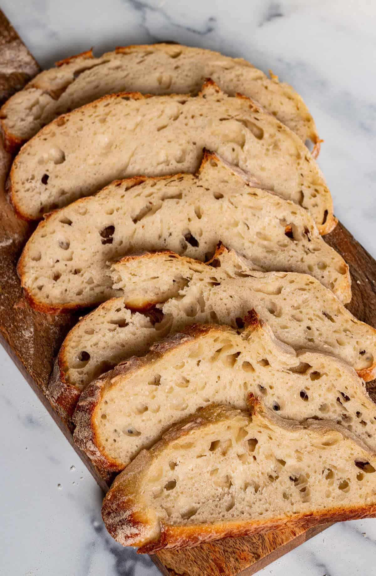 Freshly baked, and cut sourdough bread on a wooden bread board.