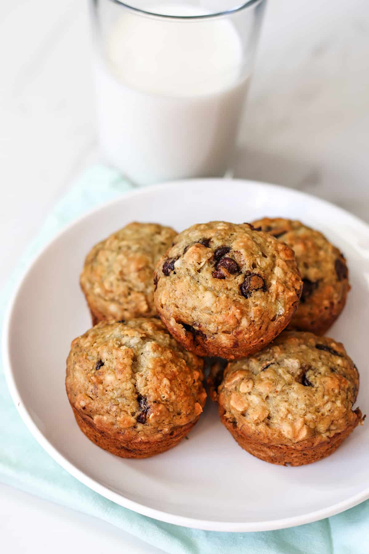 A plate with banana oat muffins and a glass of milk. 