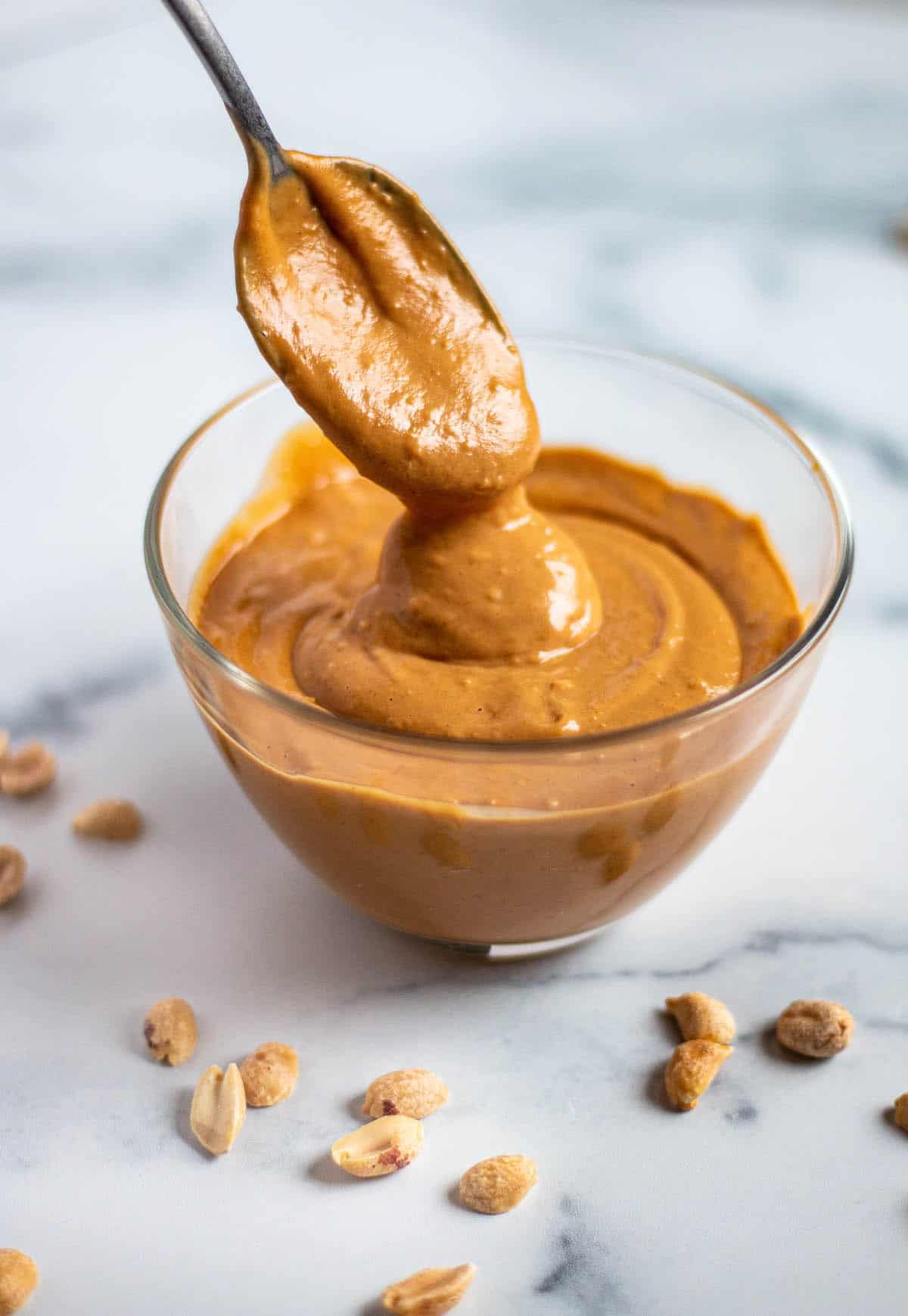 A bowl with a peanut sauce and spoon. 