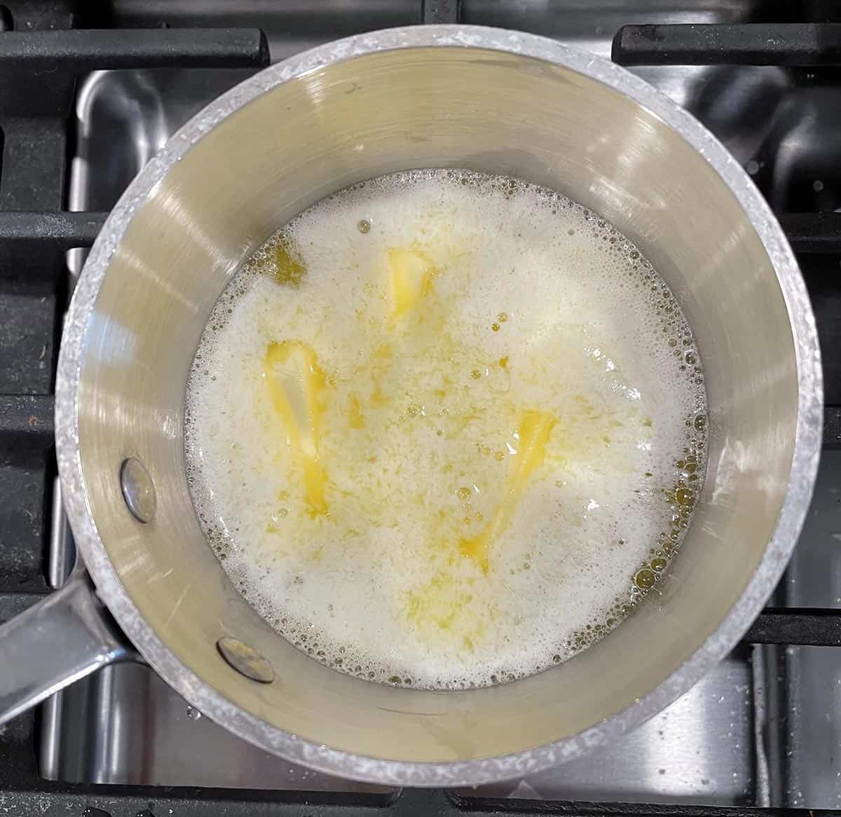Butter melting in a small sauce pan on a stove.