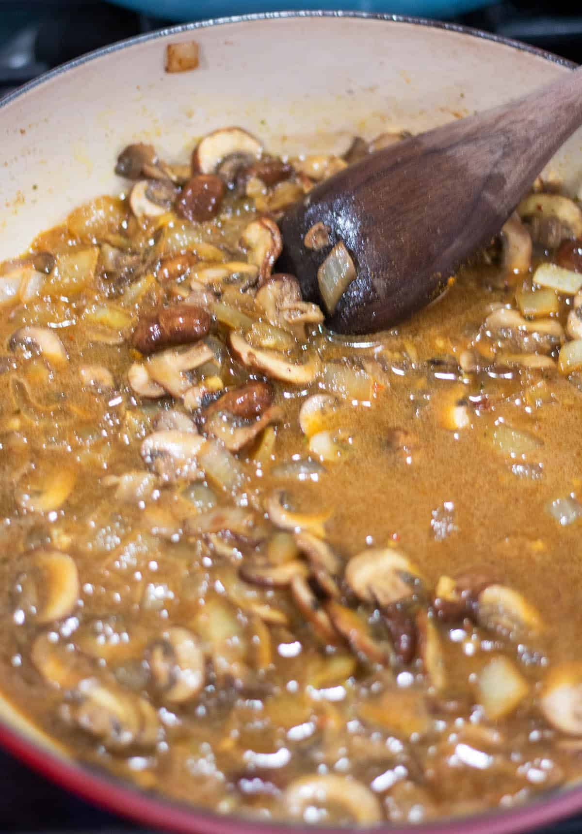Braiser with mushrooms simmering in a vegetable broth.