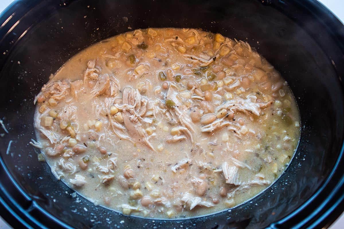 Crock-Pot full of chicken soup. Has shredded chicken, corn, white beans and chilis. 