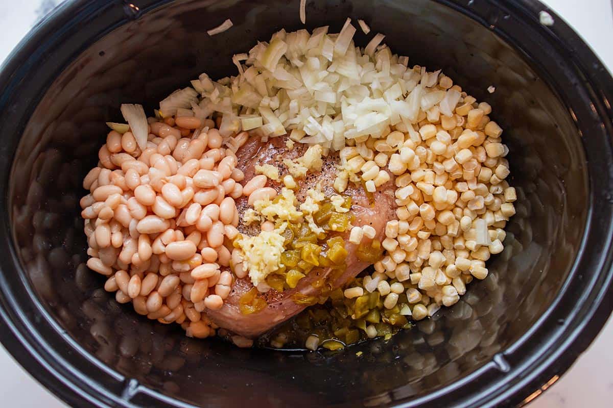 Crock-pot with frozen corn, diced onions. white beans and frozen chicken. 