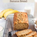 A cooling rack with a loaf of banana bread with a knife and words that say sourdough discard banana bread.