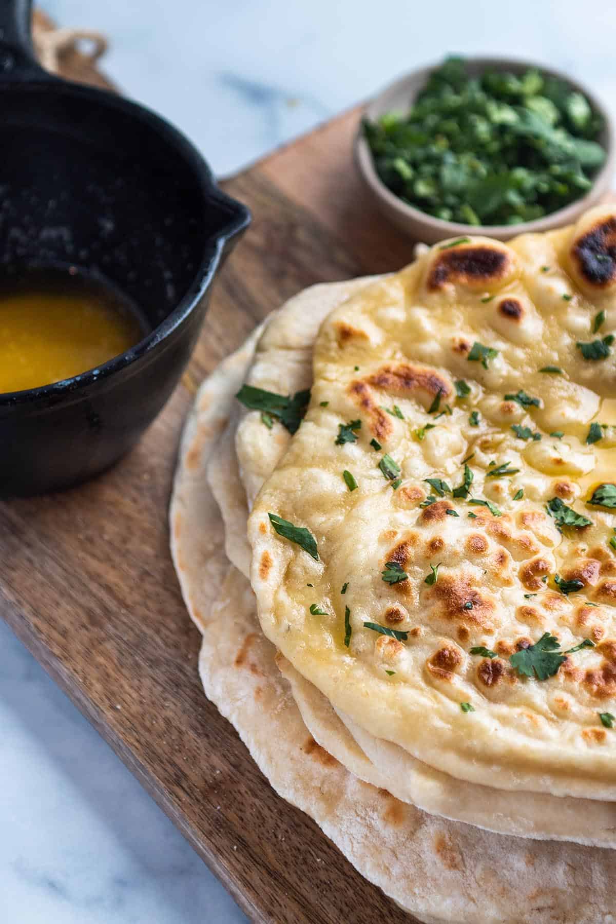 Stack of sourdough naan with butter melter and fresh cilantro. 