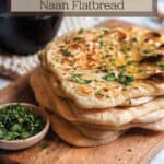 A wood board with a stack of naan flat bread with words that say sourdough discard naan flatbread.