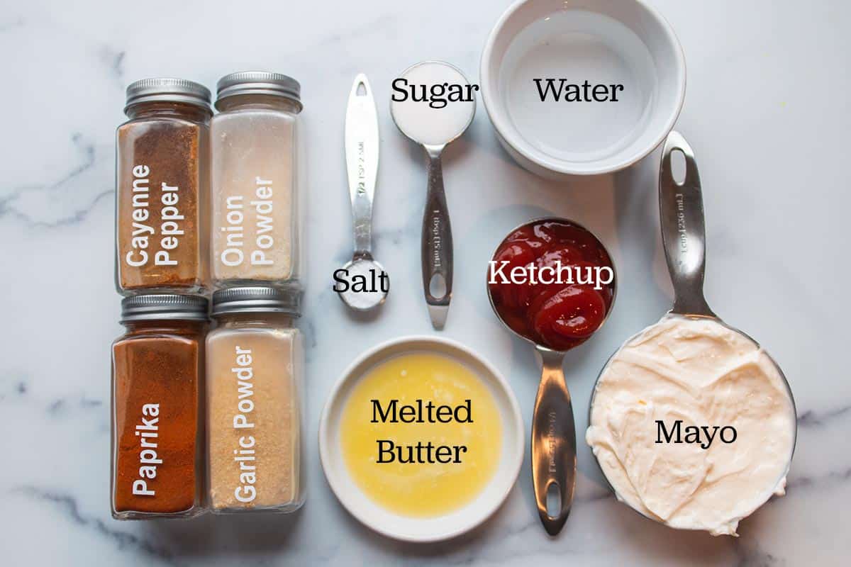 Ingredients laid out to make yum yum sauce. Water, sugar, salt, ketchup, mayo, melted butter and spices in spice jars. 