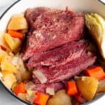 A Dutch Oven pot with a corned beef brisket, cabbage wedge, potatoes and carrots.