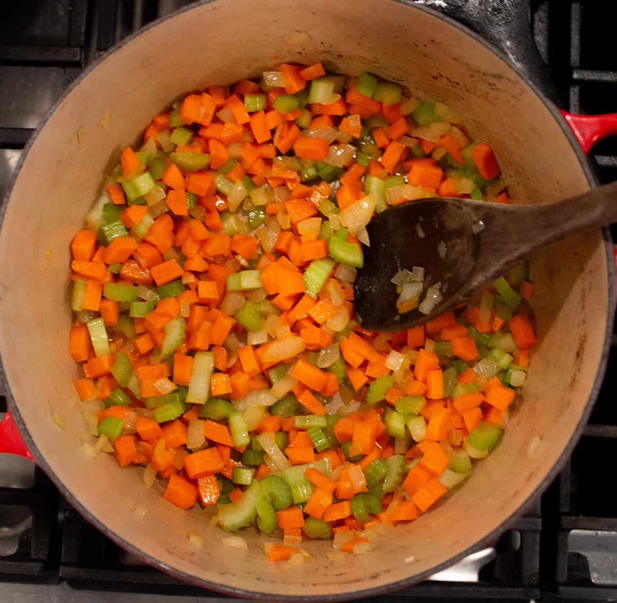 Dutch oven with diced carrots, celery and onions simmering in olive oil. 