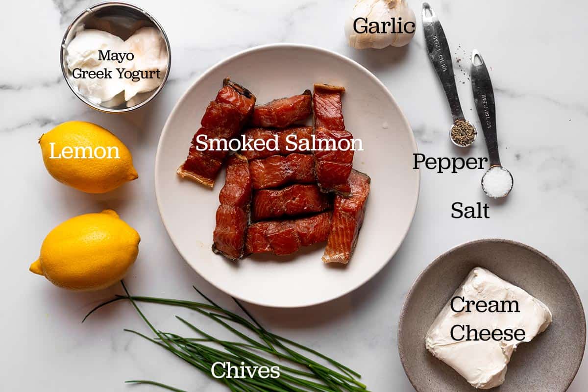 Ingredients for a smoked salmon dip. Smoked salmon, garlic, mayo, yogurt, lemons, chives, cream cheese, salt and black pepper.