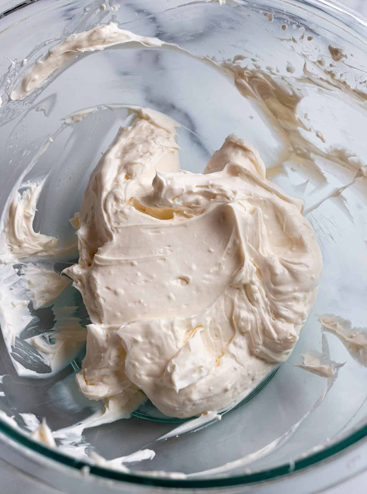 A bowl with cream cheese that has been whipped into a smooth texture. 