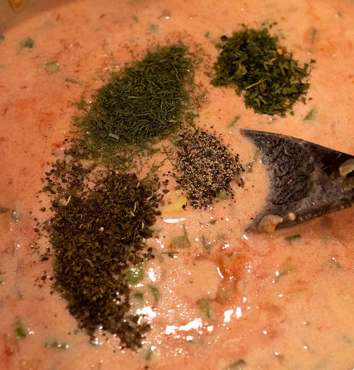 Spices being added to a smoked salmon chowder.