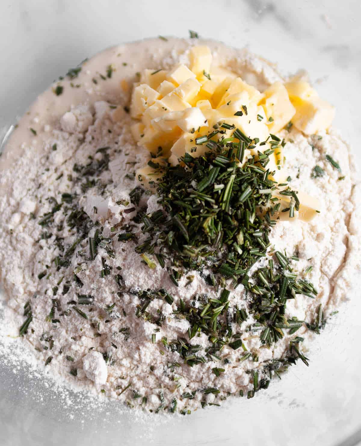 Glass bowl with flour, butter and fresh rosemary. 