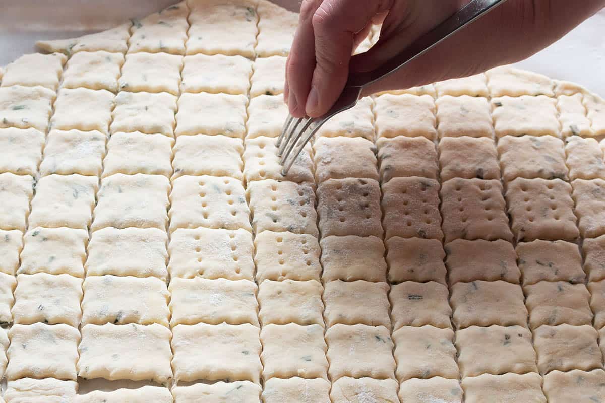 A fork poking holes into the raw sourdough cracker dough. 