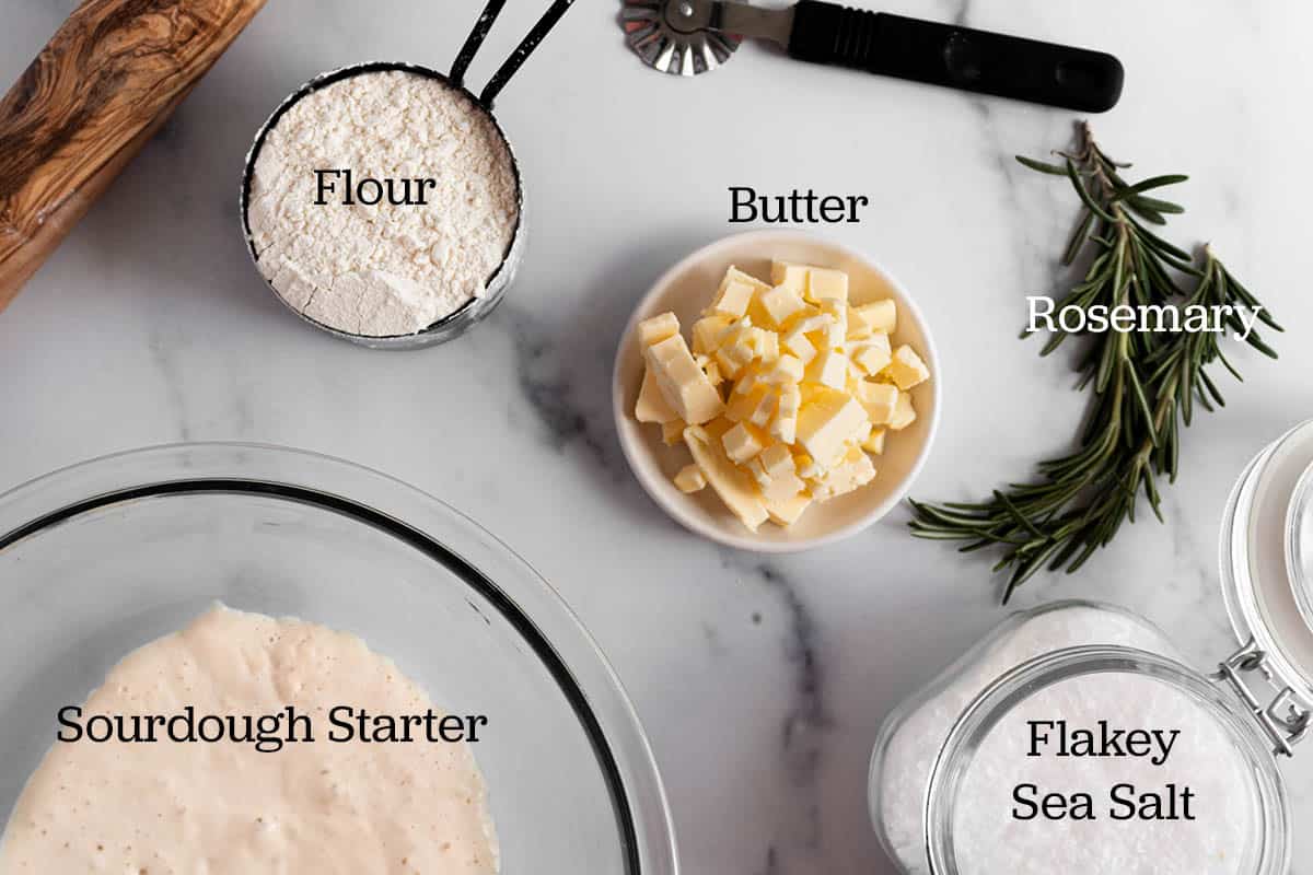 Ingredients for sourdough crackers. Flour, butter, flaky sea salt, rosemary and sourdough discard. 