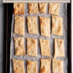 A baking sheet with rectangle sourdough discard crackers.