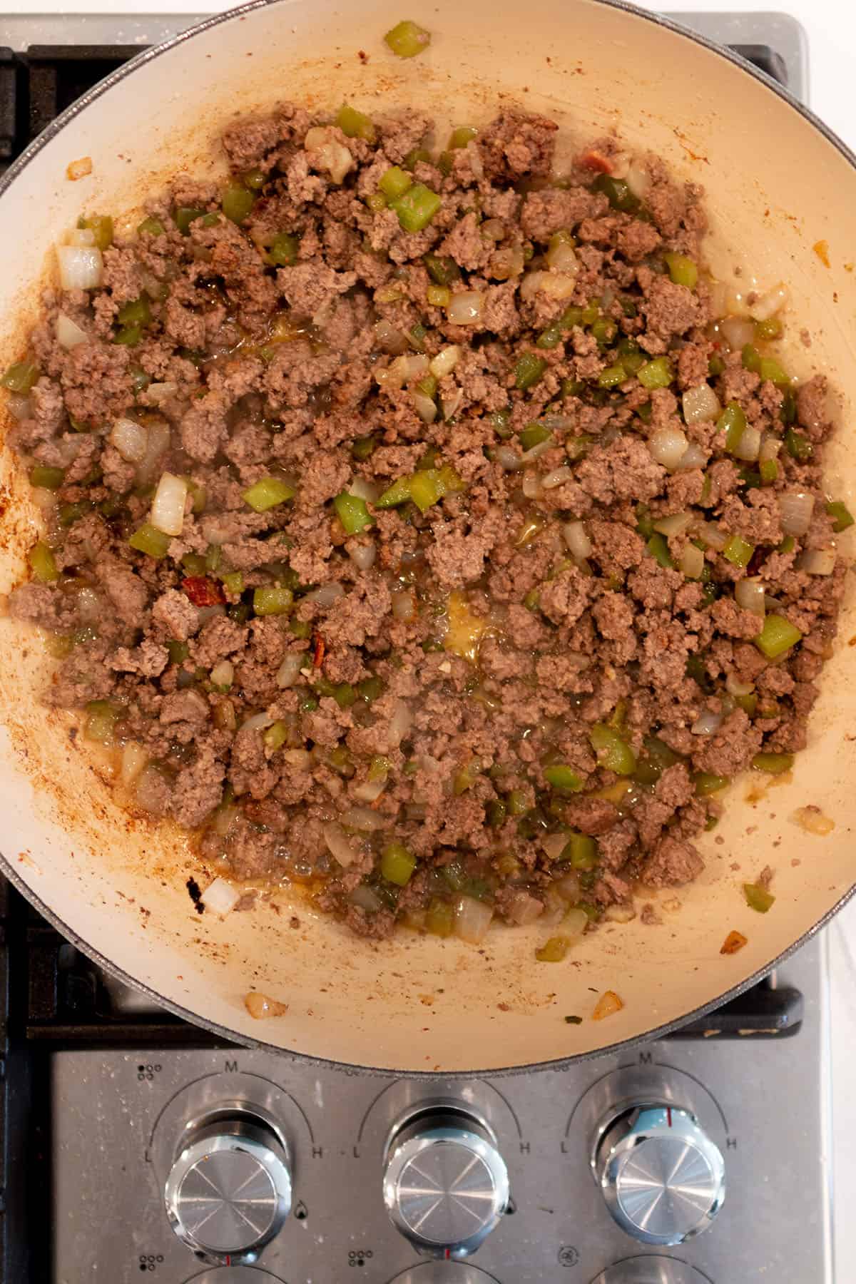 A large skillet with ground beef being browned.