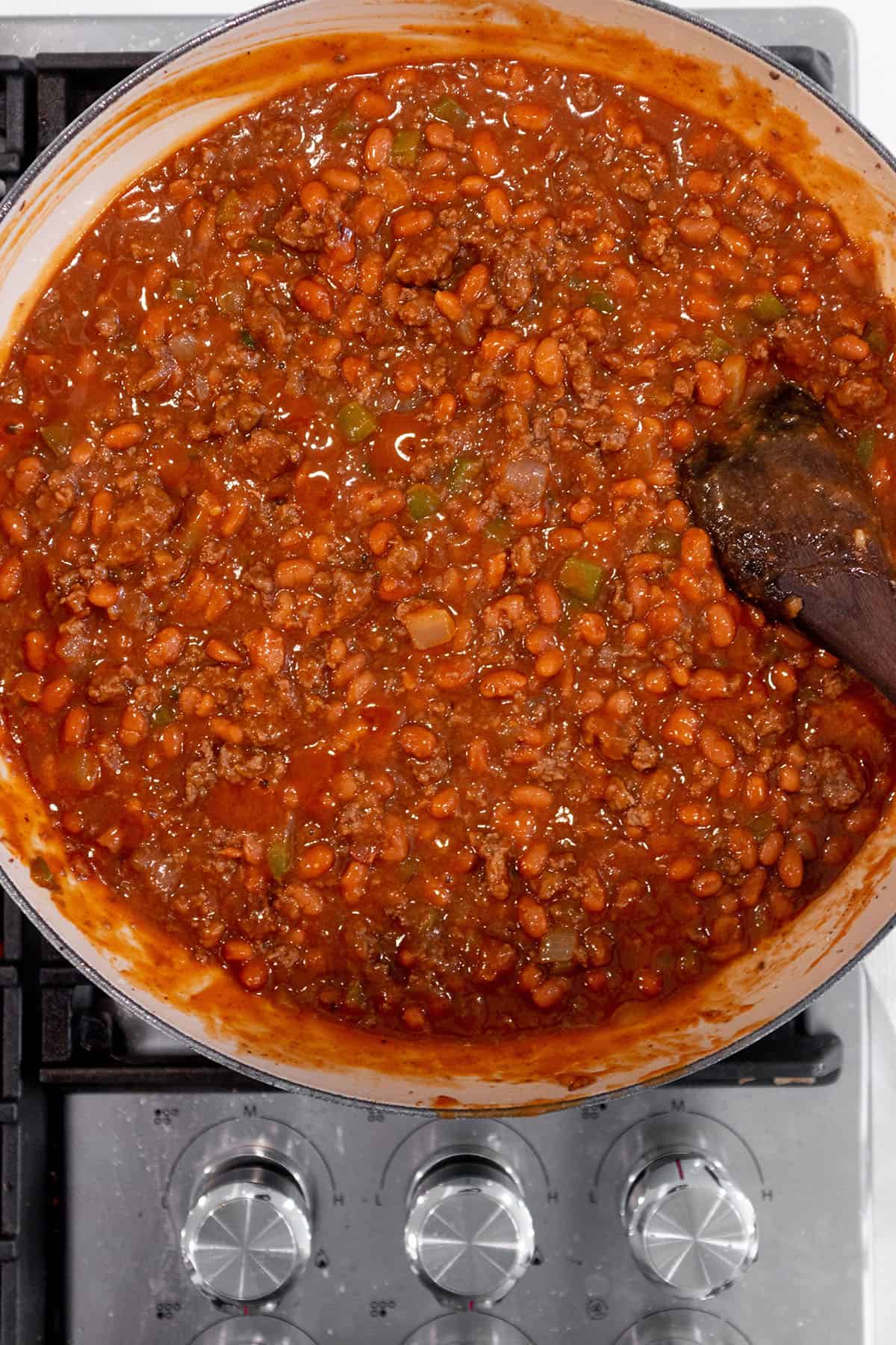 A large skillet on the stove with baked beans simmering.