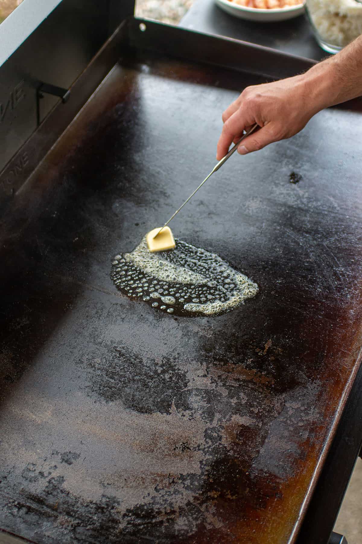 Tablespoon of butter being melted on a Blackstone.