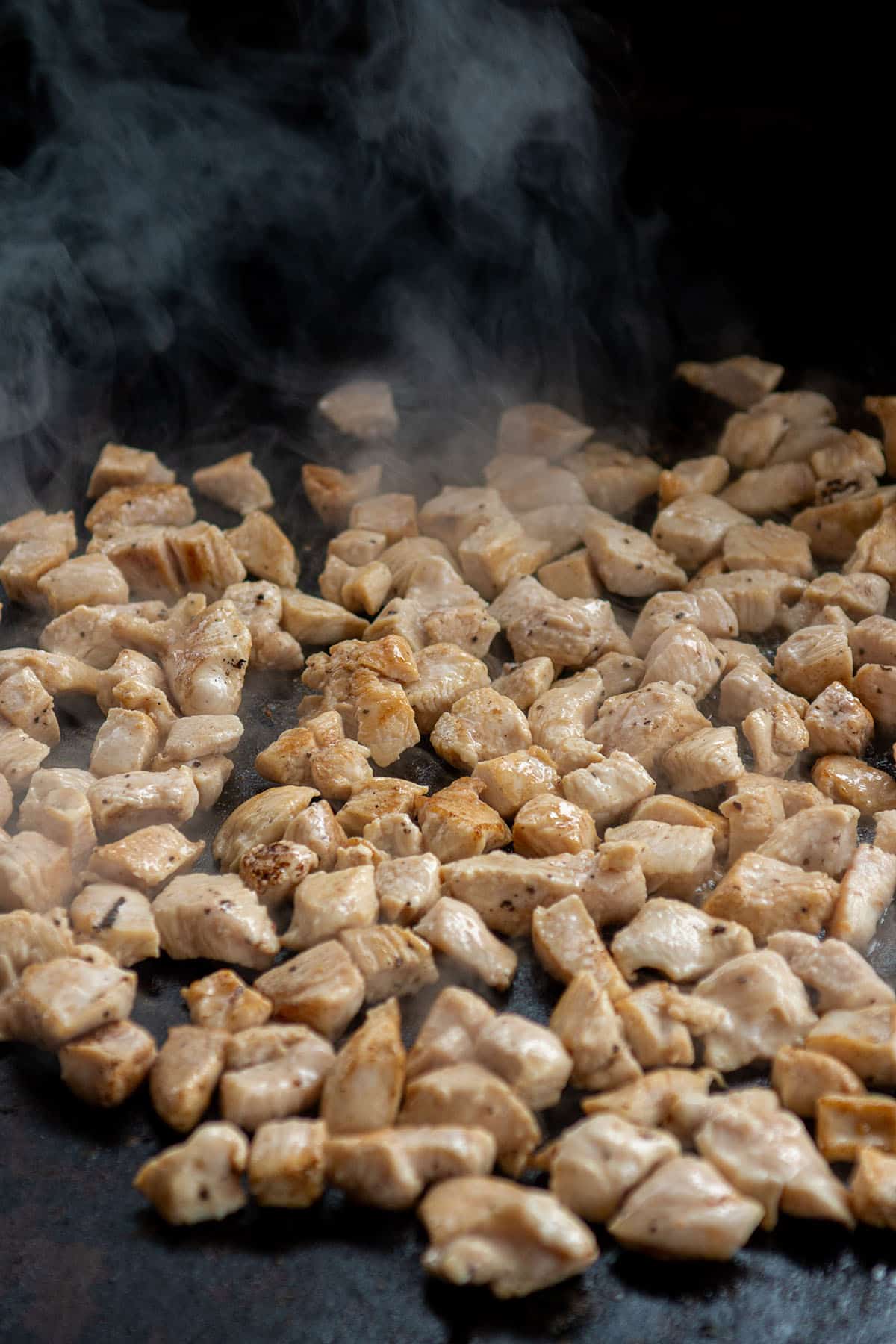 Diced chicken being browned on a Blackstone cooktop.