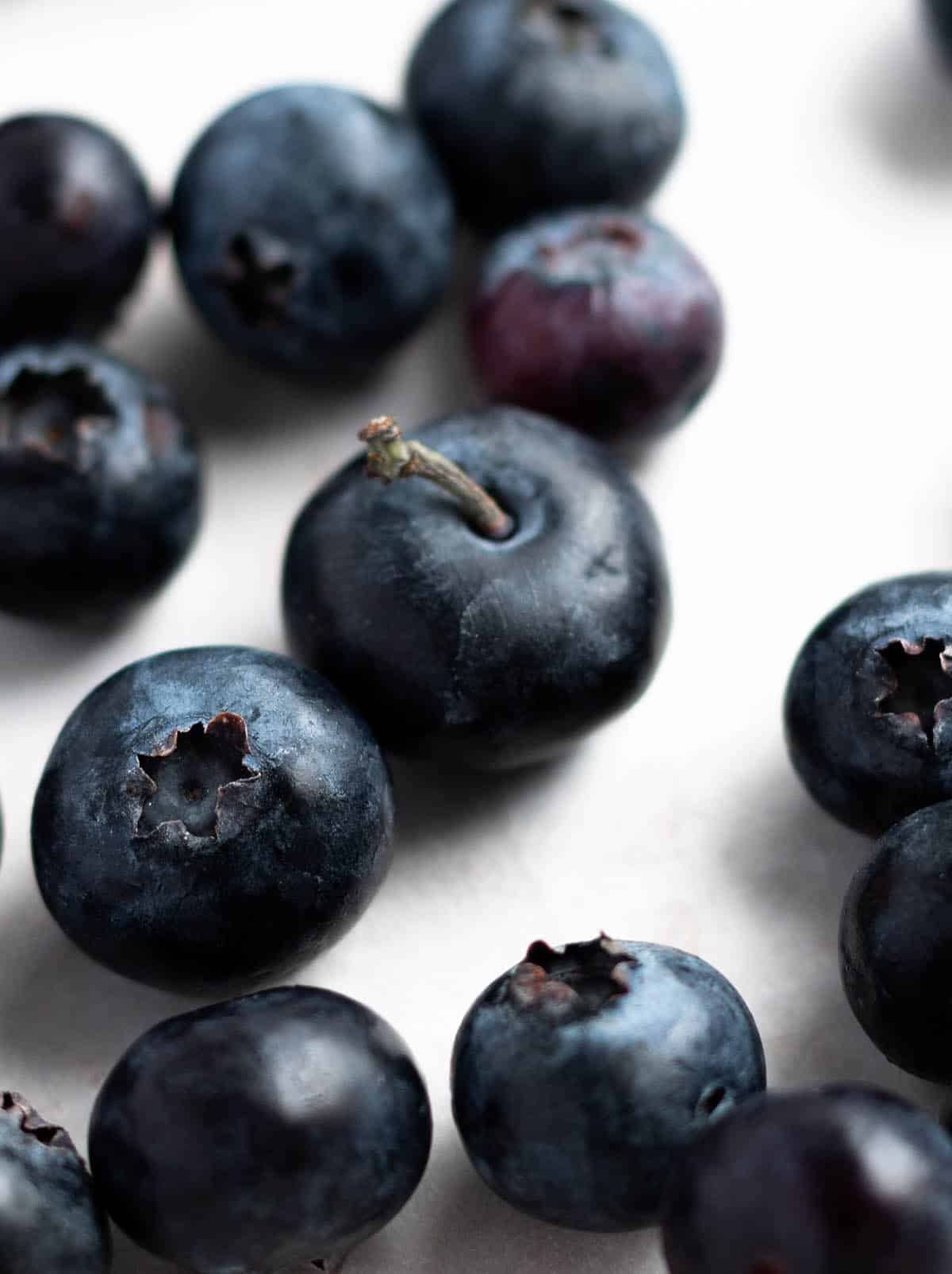 Fresh blueberries with a stems laid out on parchment paper.