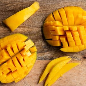 Two Large pieces of mango with a crosshatch and two smaller strips on a wooden board.