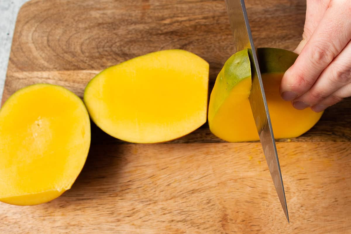 A mango with but cheeks removed and the side being cut off. 