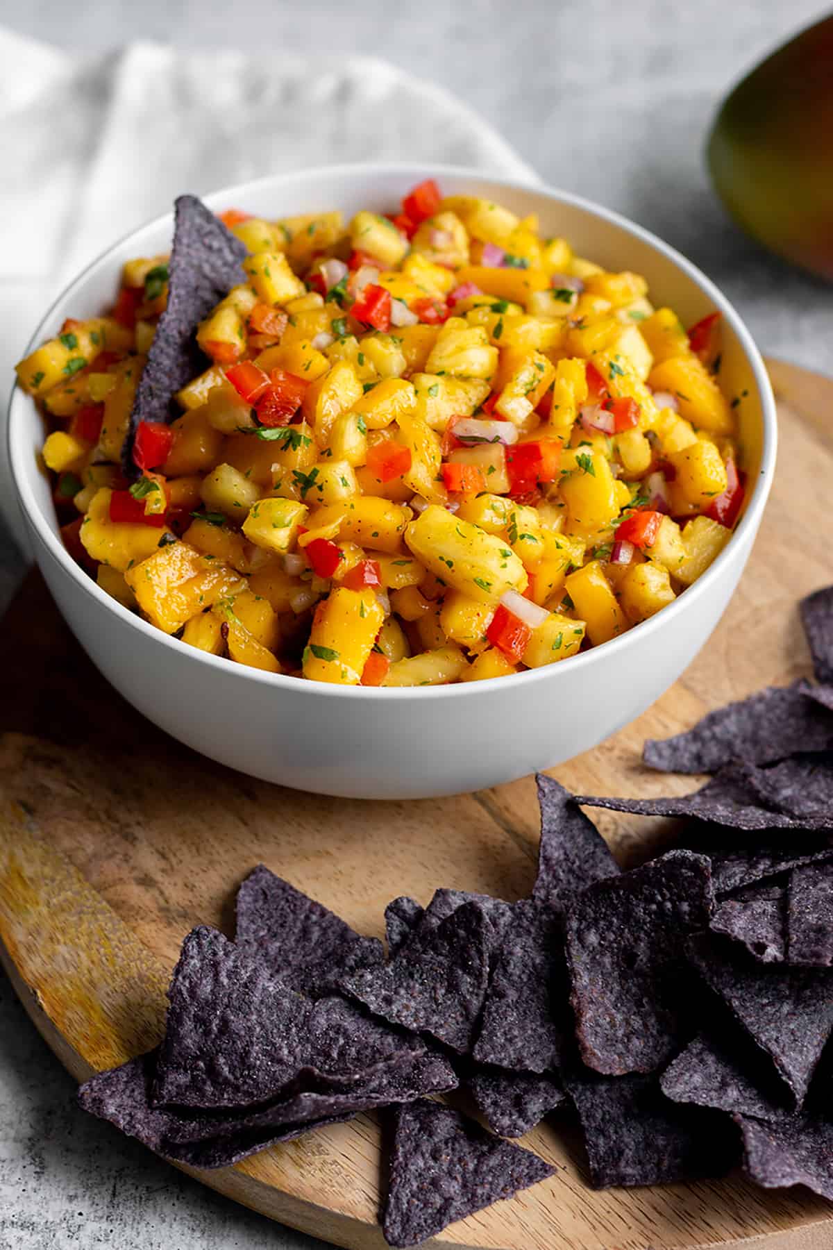 White bowl with diced mangos, pineapples and blue corn tortilla chips.