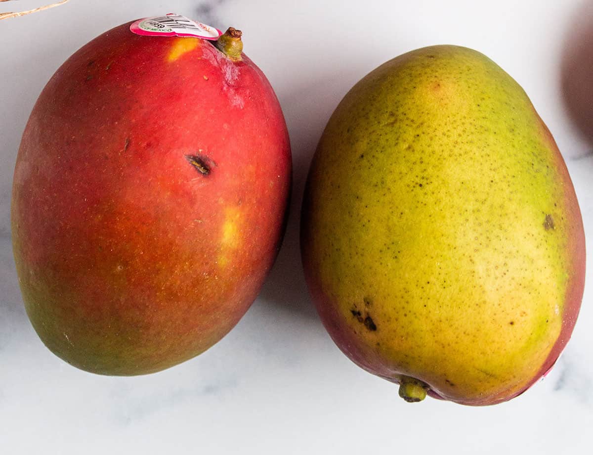 A pair of mangos, a red side and a green side.