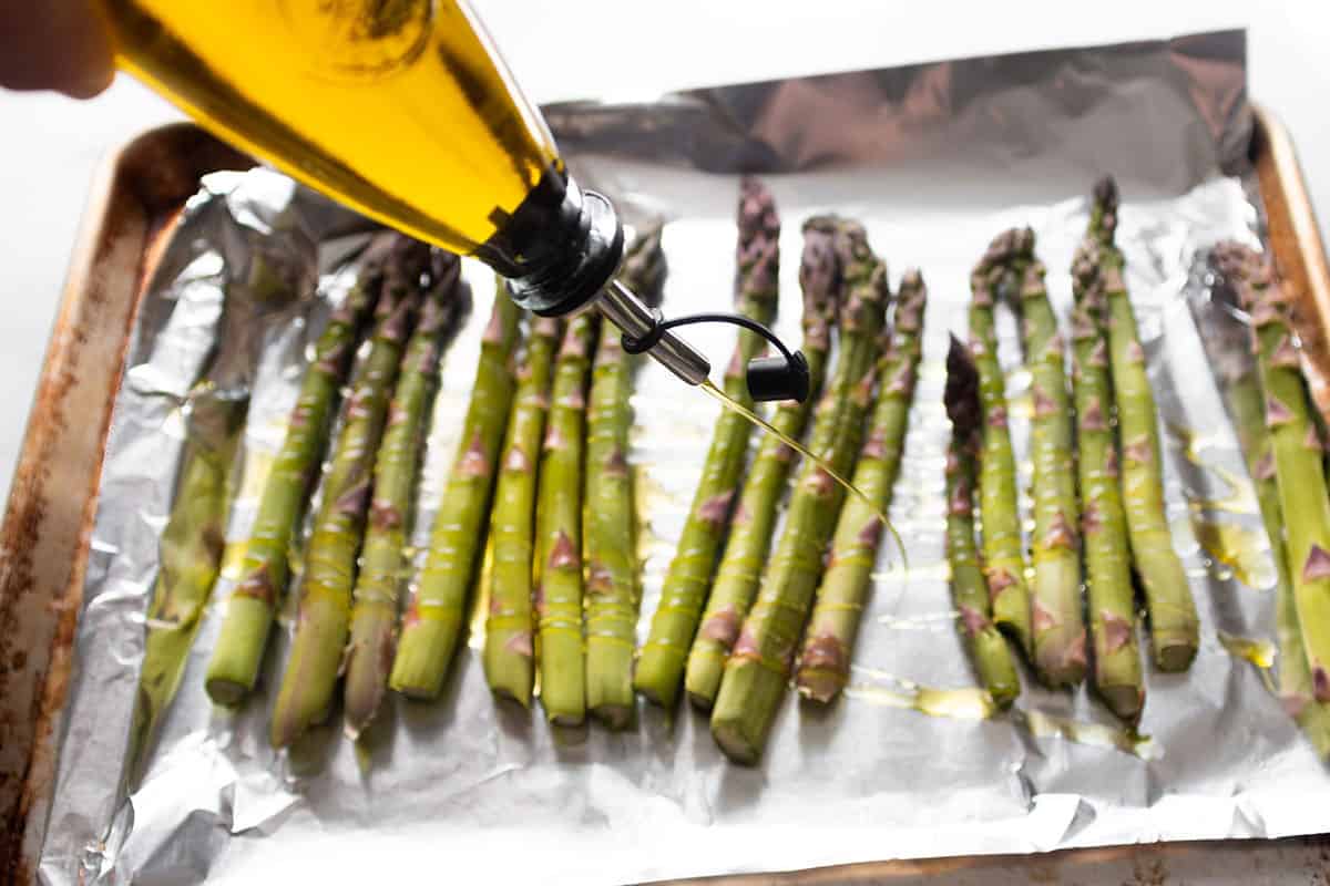 Drizzling olive oil all over asparagus.